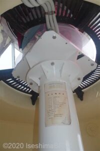 灯器を見上げたようす。灯器は鉄製の大きな白い柱の上に備えられている。