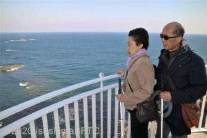 展望部分に立ち、の風を感じる視覚障害者のカップル。両者とも白状を持っている。強風なので、女性の髪は後ろにたなびいている。