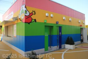 屋外にある共用トイレのようす。壁はレインボーカラーに塗られている。