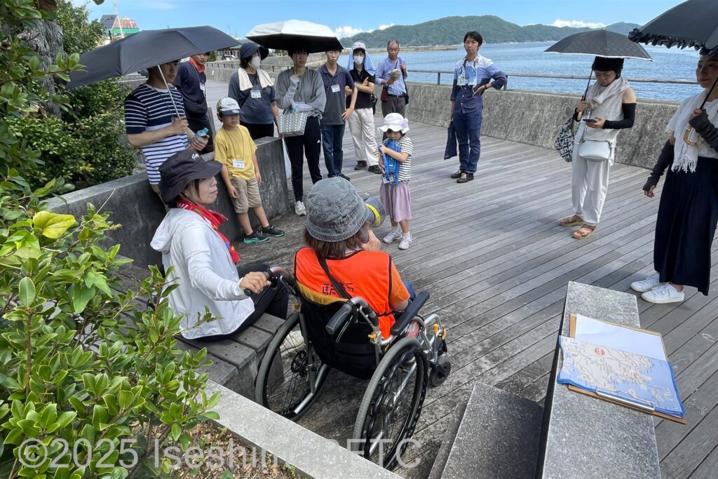 堤防沿いの遊歩道でスタッフの説明を聞くボランティアたち