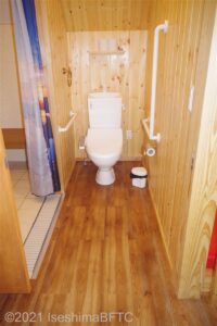 トイレのようす。便器に向かって左側の壁にL字手すり、右側の壁に横のI字手すりが付いている。横幅は87センチしかないので、車いすのままで入ることはできない。