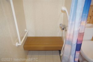 シャワールームを別角度から見たようす。ベンチとL字手すりが見える。