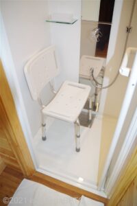 シャワールームのようす。広くはない。背もたれ付きのシャワーチェアが置かれている。