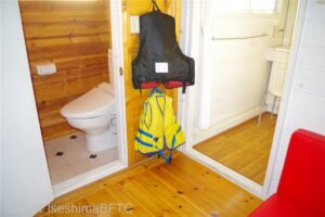 部屋の奥にあるトイレとパウダールームの入口のようす。壁にはカヌーの時に使う大人用と子供用のライフジャケットが掛かっている。