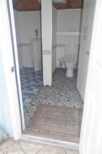 男子共用トイレ内の洋式トイレ個室のようす。カラフルなタイルが敷かれている。