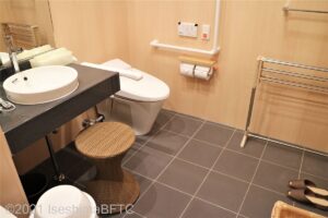 洗面台の右隣にあるトイレのようす。便器に向かって左側の壁にL字手すり、右側にI字の可動式手すりが付いている。
