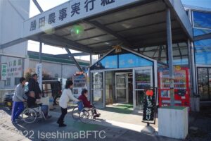 直営所の入口のようす。車いすの人2名が介助を受けながら建物の中に入ろうとしている。