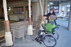 本殿で鈴を鳴らす車いす使用者