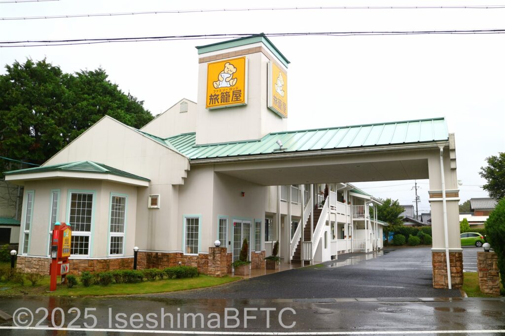 白い外壁と緑の屋根の2階建ての建物