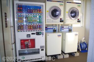 左から飲み物の自動販売機　コインランドリー2基が並ぶ