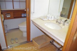 洗面所のようす。
洗面所の奥にあるトイレにはいるための縦型手すりが、トイレのドアの右側の壁についている。