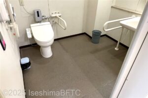 シンフォニアテクノロジー響ホール伊勢　事務室前車いす対応トイレ　入口から室内を見たところ　入口正面にたて置きに便器、右手前に洗面台