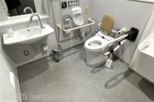 三重県営陸上競技場管理棟1階車いす対応トイレ　内部　入口から見て右奥に、よこ置きに便器がある。入口からみて正面に洗面台