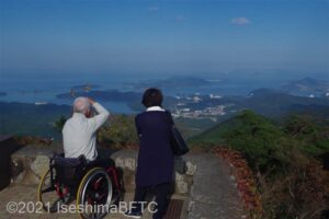 展望足湯付近で眼下の絶景を楽しむカップル。男性は車いすに乗っている。