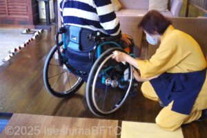 車いすのタイヤを拭いてもらっているようす