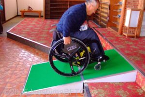 簡易スロープを上がる車いすの男性