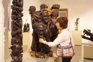 何人もの顔と身体が一体になった彫刻をさわる視覚障害者