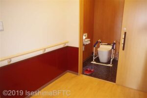 客室のトイレのようす。洋式便器にはめ込む形式の簡易手すりが付いている。