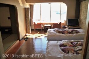 洋室のようす。右にベッドが2台。奥の窓際にはイス2脚と小さなテーブルが置かれている。