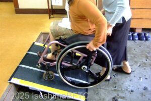 簡易スロープを上がる車いすの女性