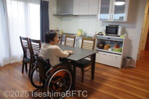 ダイニングのテーブルにつく車いすの女性