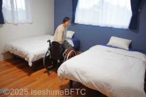 洋室2のベッドへ腰かけようとする車いすの女性