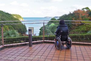 外部テラスから外を眺める車いすの女性のようす。