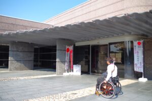 博物館の入口を見る車いすの男性