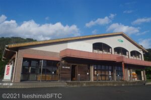 志摩市観光協会志摩支所の外観。赤い大きな傾斜の切妻屋根を持つ建物になっている。