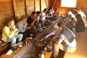掘りごたつタイプの海女小屋でたくさんの外国人観光客が食事をしているようす。
