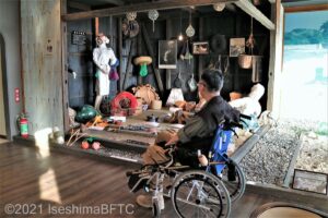 海女資料館に展示されている漁具などを眺める車いすの男性のようす。