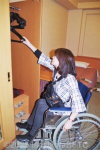 413号室　クローゼットへハンガーをかける車いすのお客さま