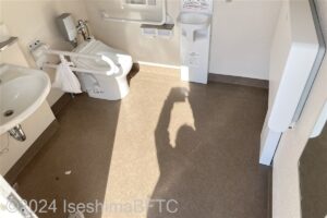 磯部ふれあい公園車いす対応トイレ内部　入口からみて左奥に、よこ置きに便器。入口からみて左手前に洗面台