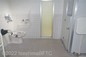 阿児ふるさと公園車いす対応トイレ内部　入口からみて左奥に、よこ置きに便器。入口からみて左手前に洗面台