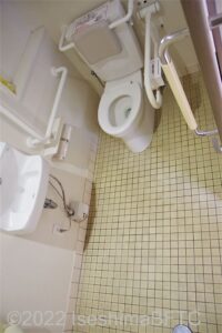 賢島駅南口駐車場車いす対応トイレ室内　入口からみて右に、よこ置きに便器。入口正面に洗面台