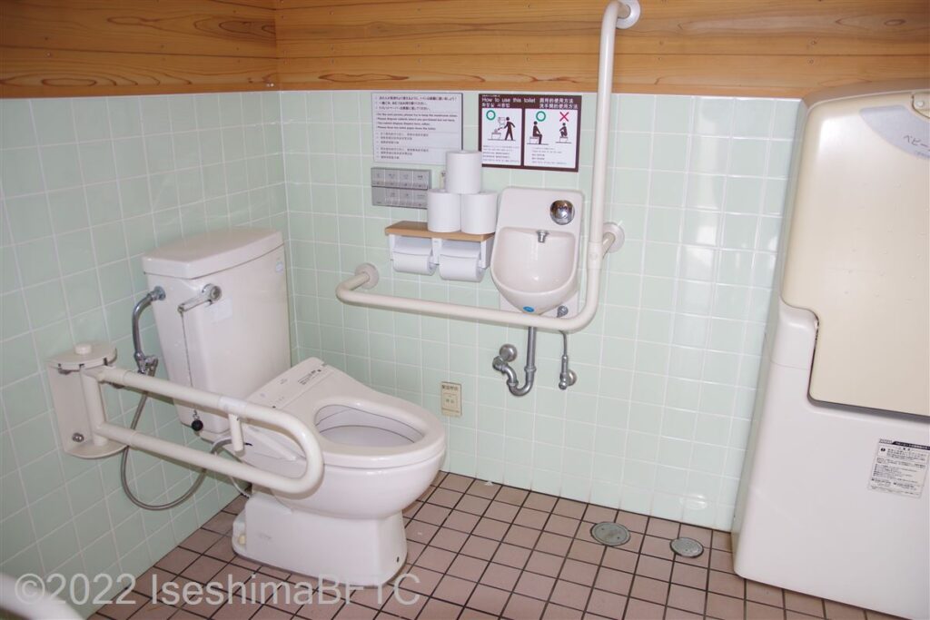 横山展望台駐車場車いす対応トイレ便器まわり　便器に向かって右側にL型固定手すり、左側にU型可動手すり