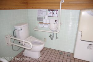 横山展望台駐車場車いす対応トイレ便器まわり　便器に向かって右側にL型固定手すり、左側にU型可動手すり