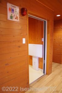 創造の森横山作業所　車いす対応トイレ入口　入口からみて左奥に、たて置きに便器。入口からみて右奥に洗面台