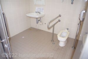 あづり浜車いす対応トイレ内部　入口からみて正面に、たて置きに便器。入口からみて左奥に洗面台