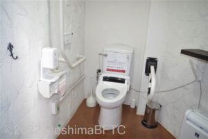 志摩地中海村　フロント横車いす対応トイレ内部内部　入口からみて正面に、たて置きに便器。洗面台は個室外