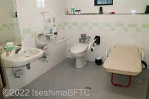 海ほおずき車いす対応トイレ内部　入口からみて左奥に、たて置きに便器。入口からみて左手前に洗面台