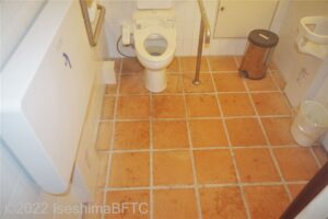 車いす対応トイレの個室内のようす。便器に向かって左側奥の壁にはL字手すり、右側にはI字手すりが付いている。