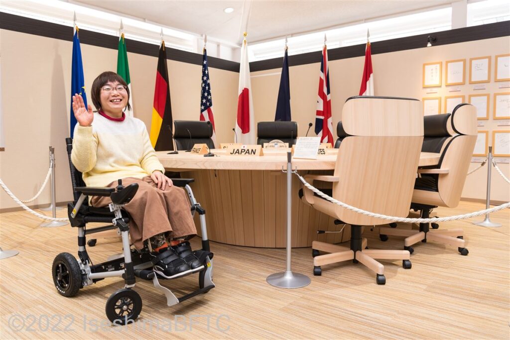 伊勢志摩サミットで実際に使われた円卓の前で記念撮影する車いす使用者