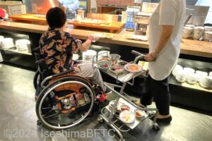 おもいやりカートを利用して料理をとる車いす使用者