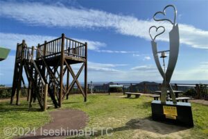 見江島展望台の広場のようす。地面には芝生が植えられていて、右手に金属でできたハートのモニュメント、左手には木製の展望デッキが見える。