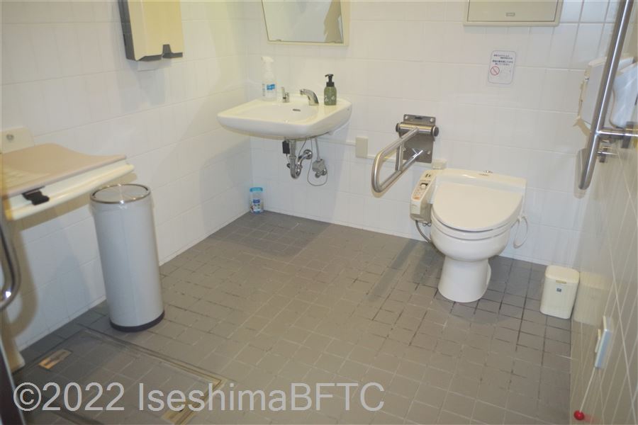 ひまわりの湯車いす対応トイレ　入口からみて左奥に、よこ置きに便器。入口からみて右奥に洗面台