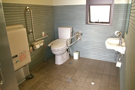 国崎漁港公衆トイレ内部　入口からみて左奥に、たて置きに便器。入口からみて右奥に洗面台